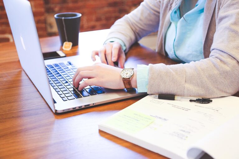 Woman doing research at a computer with an open textbook.